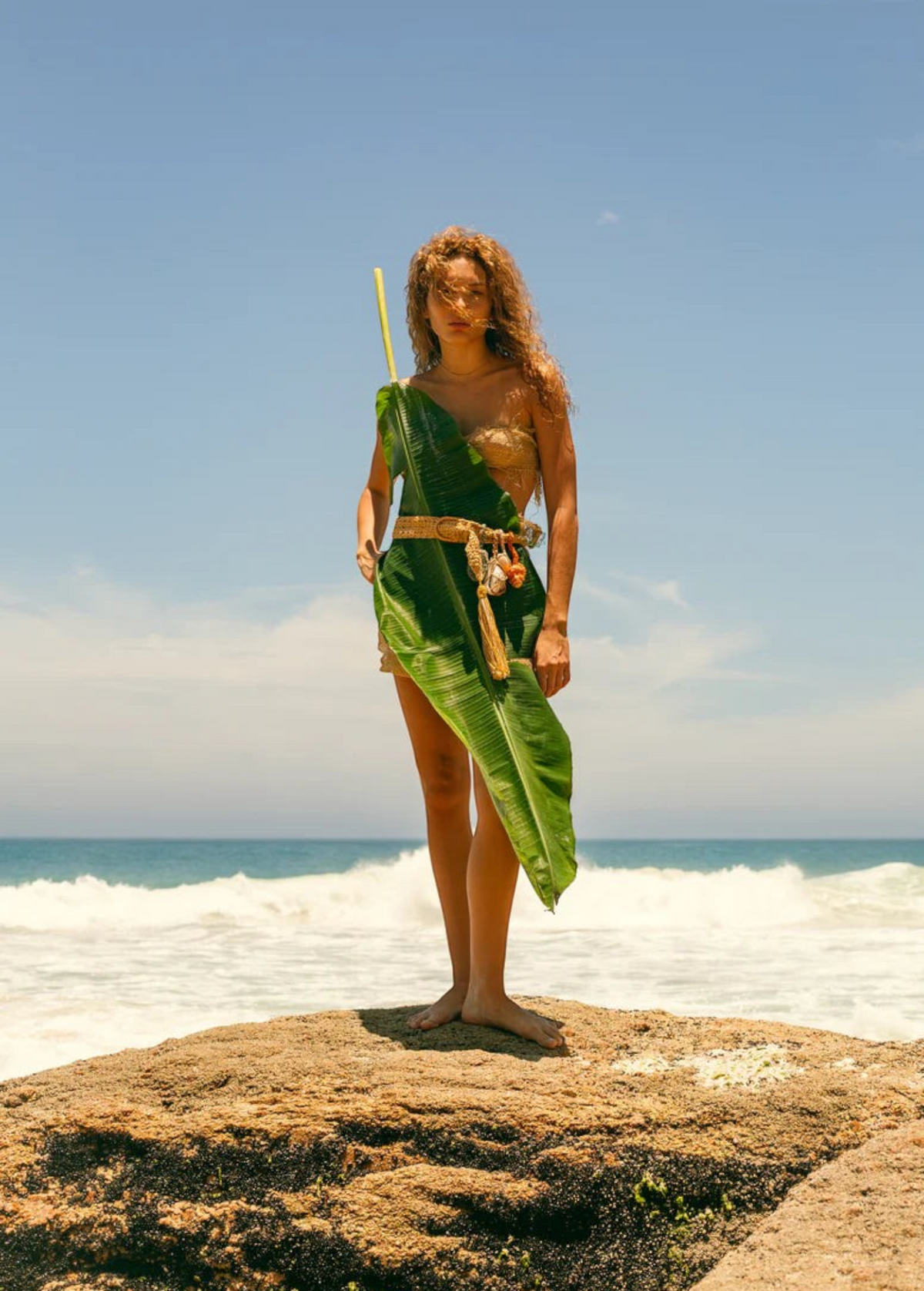 KABE SHOP INC Jibe belt featuring natural shell adornments worn by a woman on a beach with a large tropical leaf