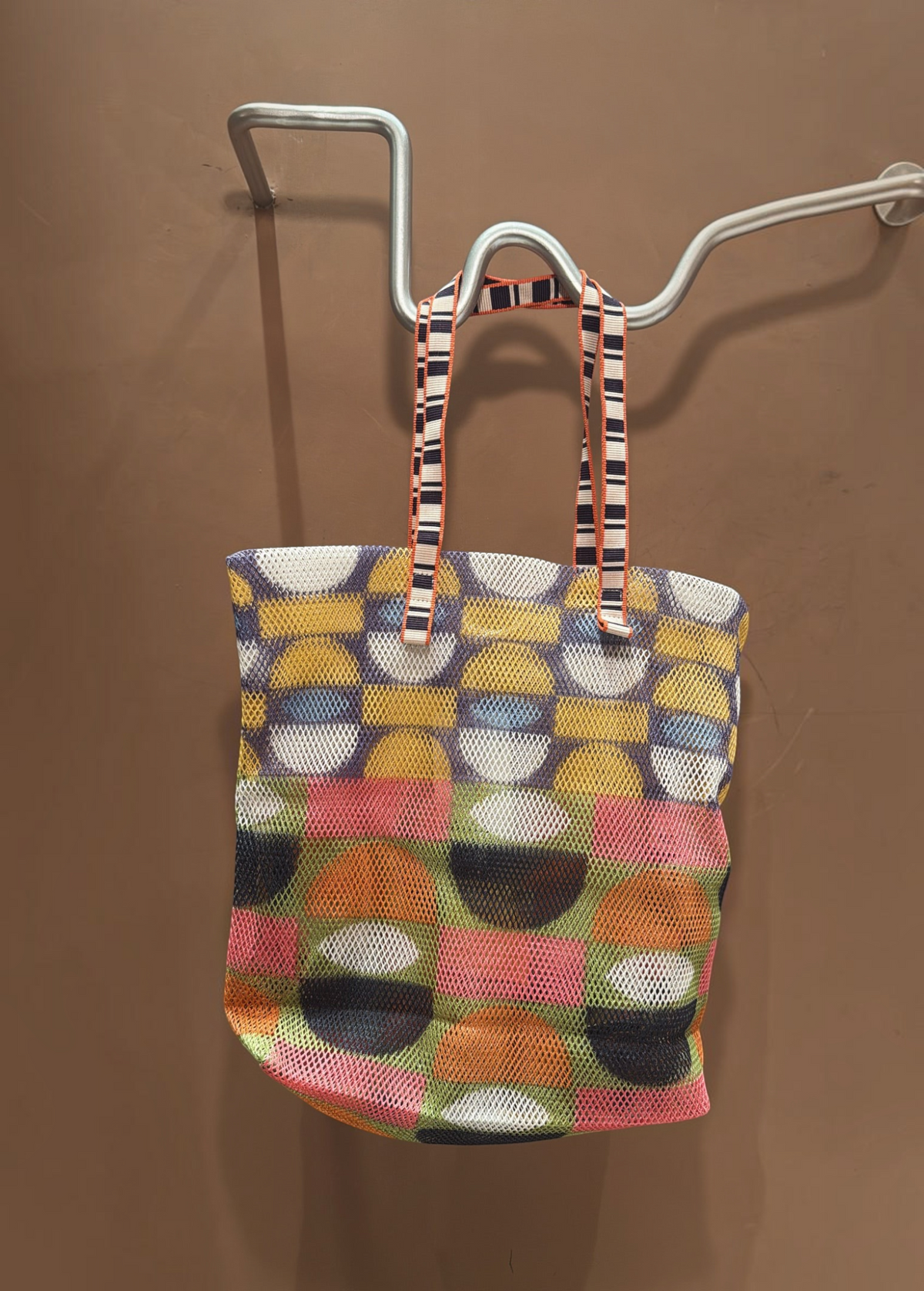 KABE SHOP INC Kanpur bag featuring a vibrant geometric mesh pattern in multi-colored circles and striped handles.