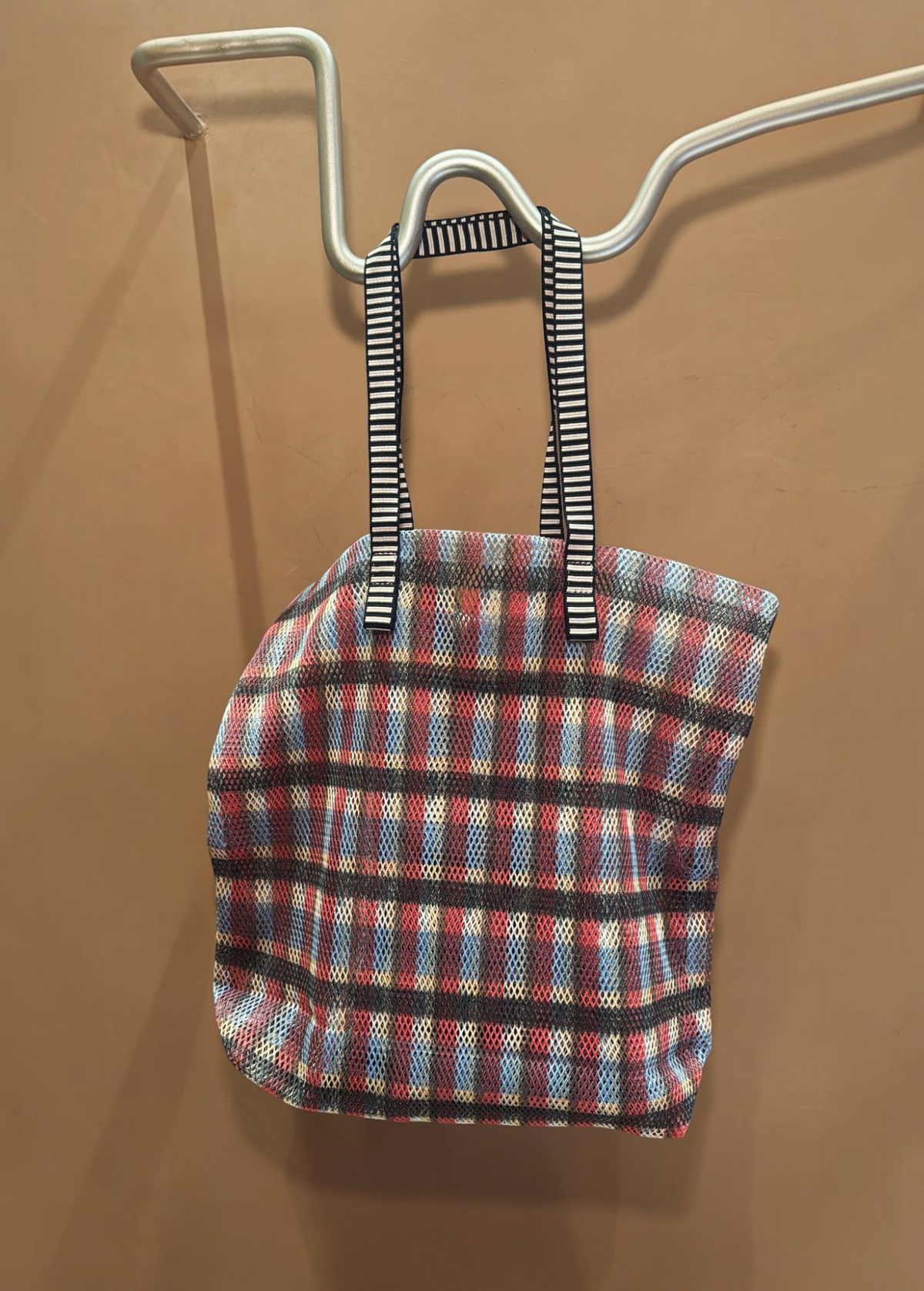 KABE SHOP INC Kanpur bag featuring a vibrant multi-colored plaid mesh pattern with black and white striped handles.