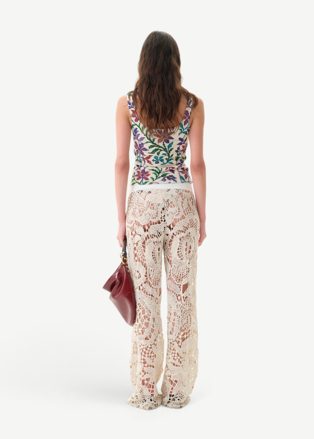 KABE SHOP INC Cali Top featuring a colorful floral print, worn with cream crochet lace trousers and a maroon bag.