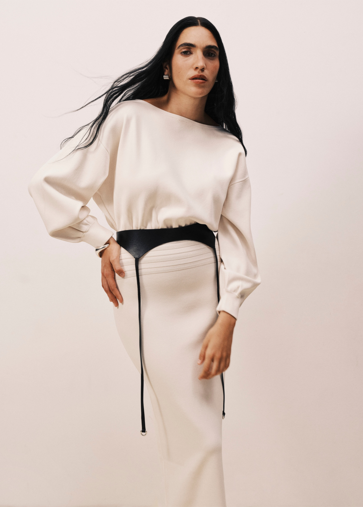 Model wearing KABE SHOP INC Laisse black Italian calfskin garter belt over a cream long-sleeve dress