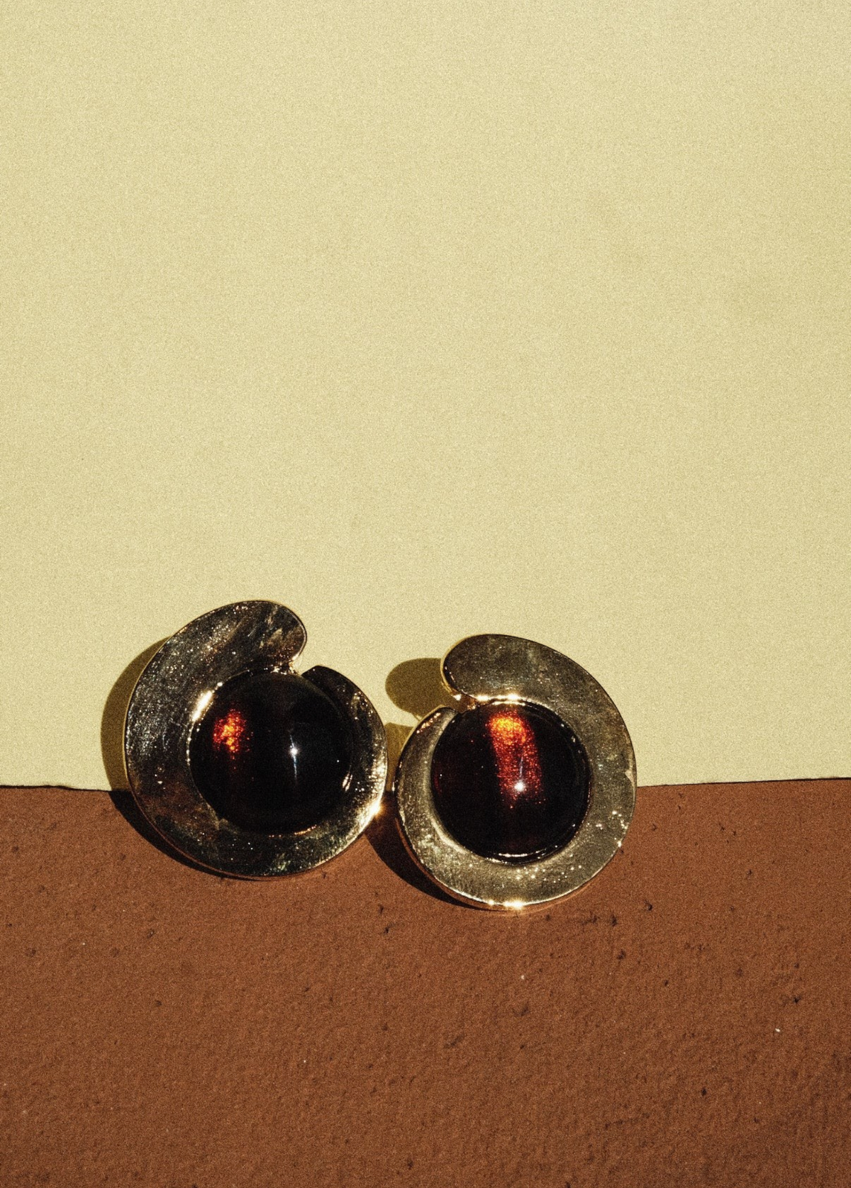KABE SHOP INC tortoise stone earrings featuring a sculptural gold-plated frame and warm brown resin inlay.
