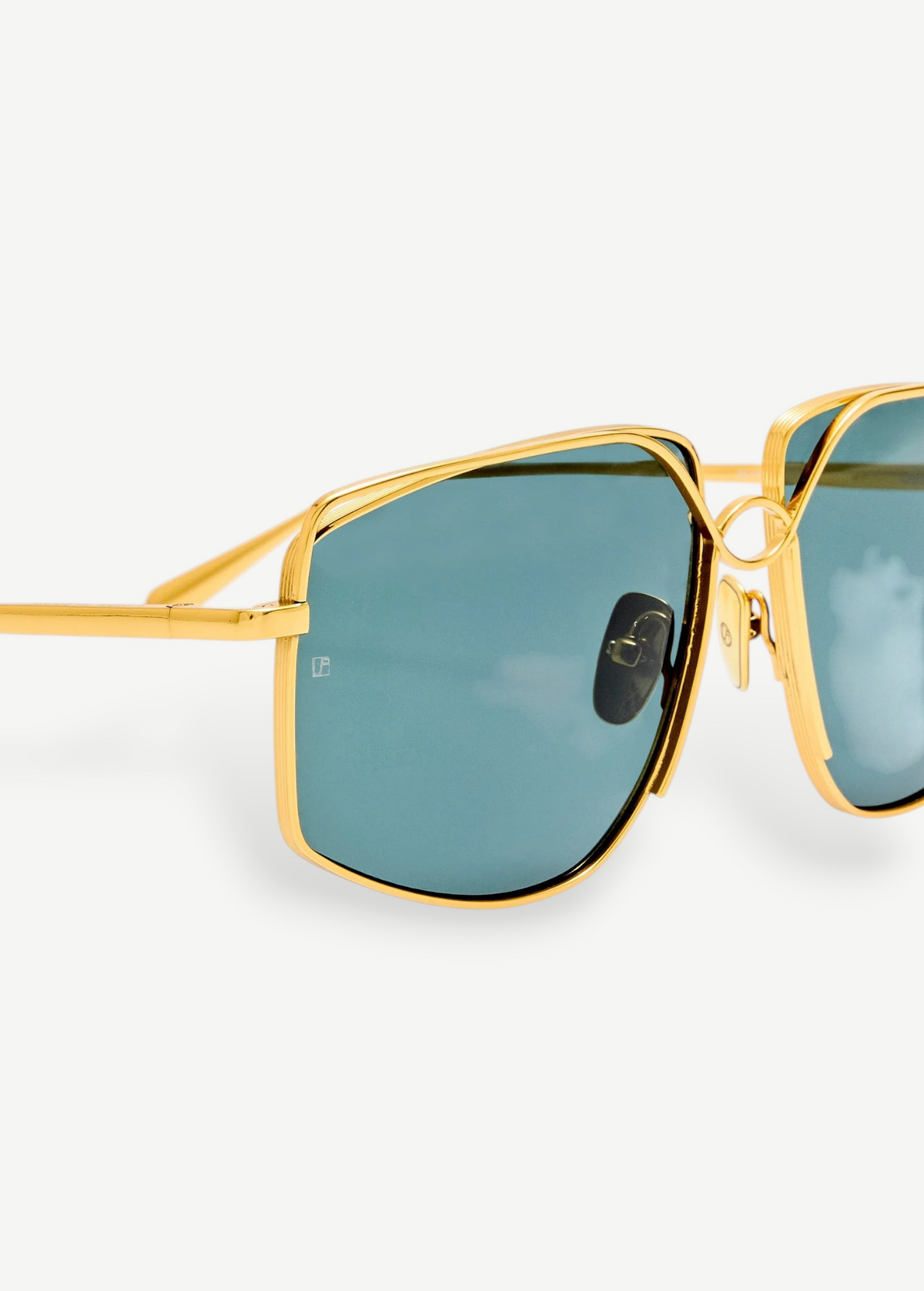 Close-up of the Miranda Sunglasses, featuring an oversized frame with gold-plated metal accents and green-tinted square lenses, shown against a plain white background.