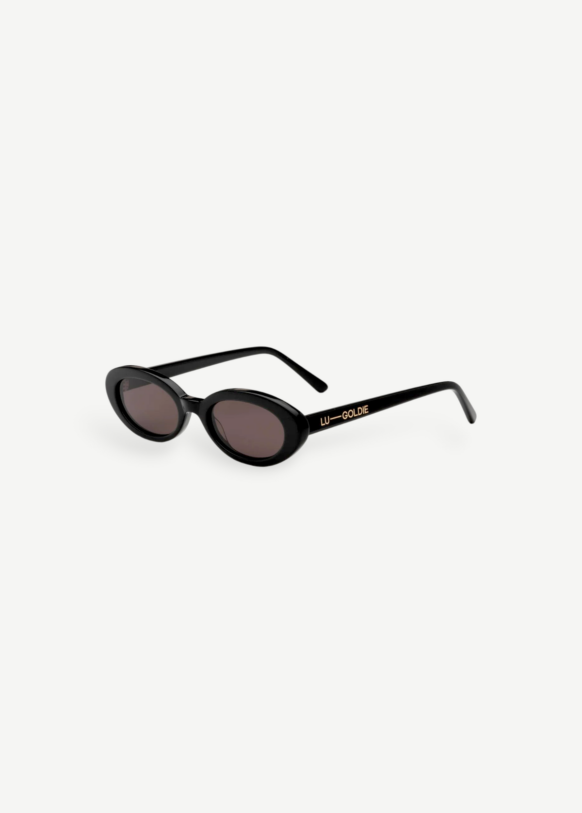 Certainly! Here’s a rewritten version using your product data: The Sylvie sunglasses feature black, oval-shaped frames with dark lenses and bold, thick sides adorned with LU—GOLDIE in gold lettering on the left arm, all showcased against a crisp white background—a true pocket rocket accessory that complements any vintage suit.