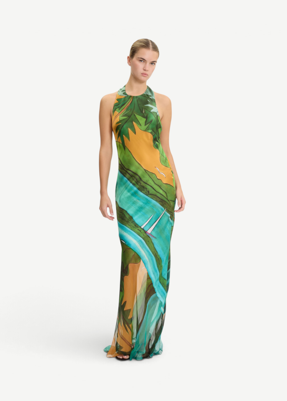 Model wearing KABE SHOP INC Magdalena long silk maxi dress with halter neckline and landscape print in green and gold