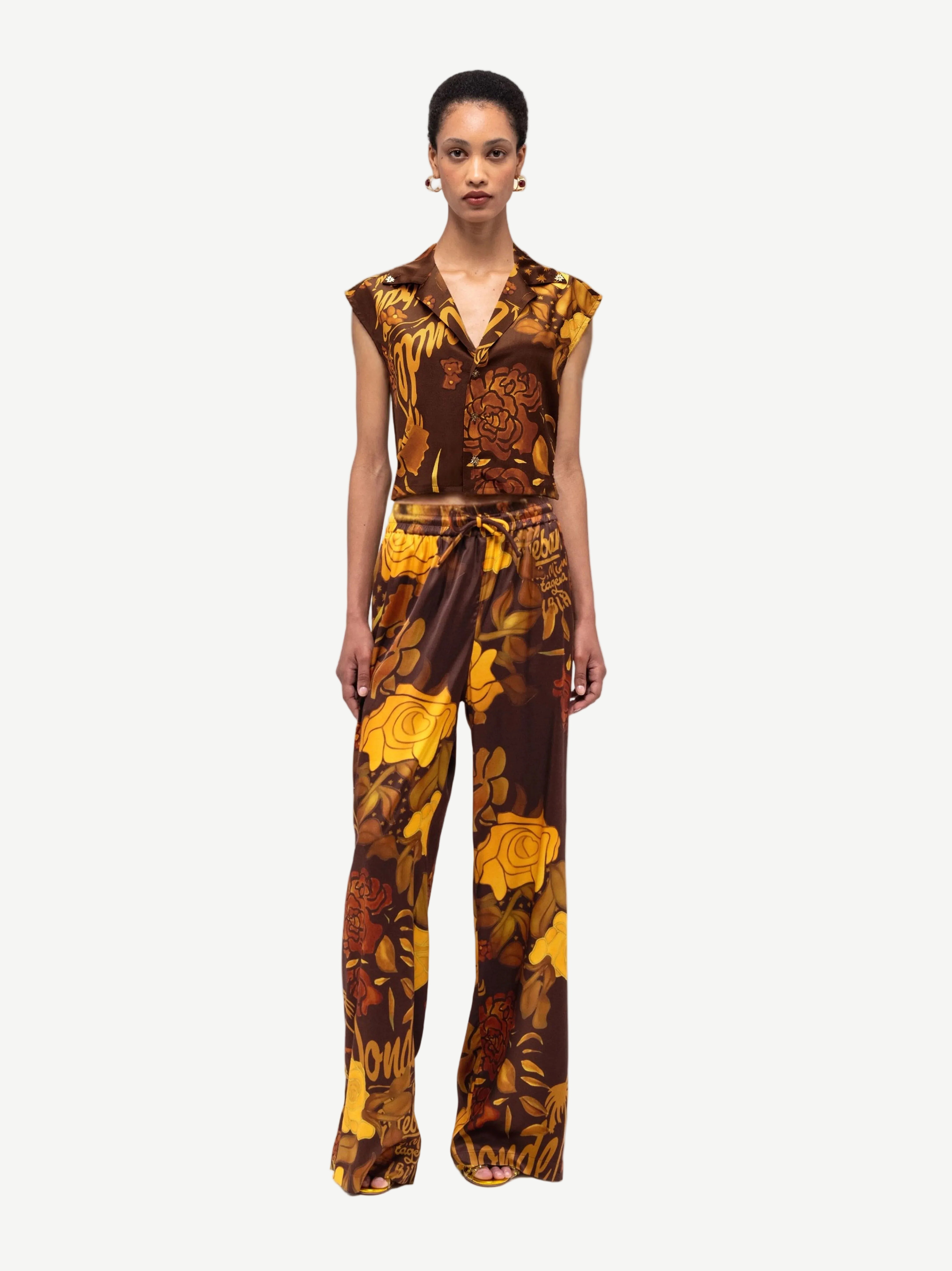 Woman wearing a brown and yellow floral patterned jumpsuit on a white background