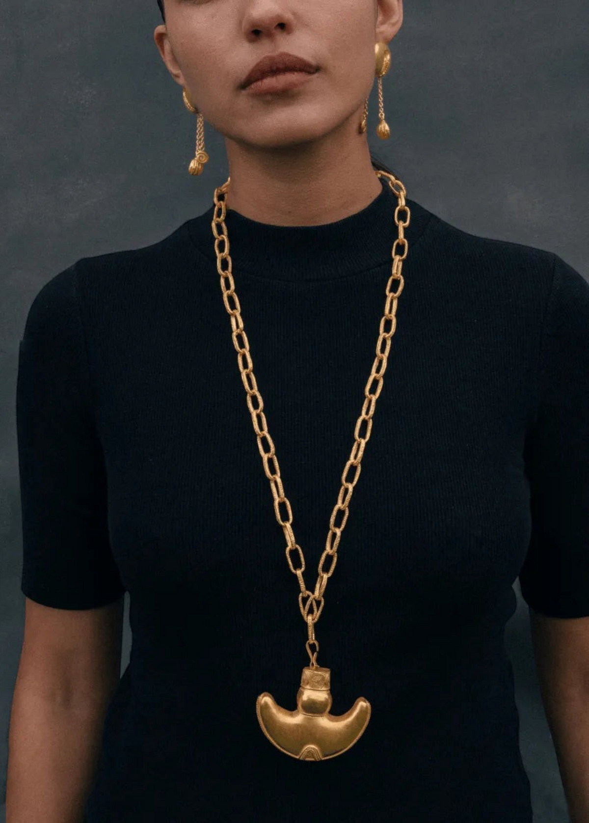 KABE SHOP INC Wanpu necklace featuring a gold anthropomorphic pendant on a chunky chain worn by a model