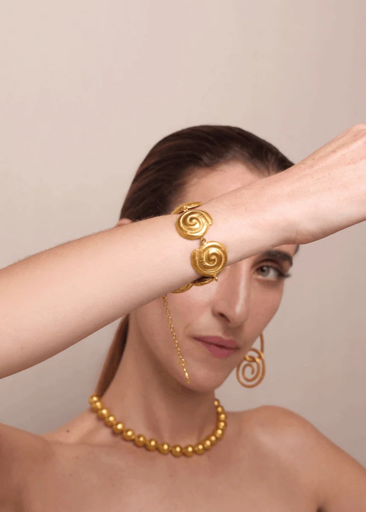 KABE SHOP INC Allinmi bracelet featuring gold spiral Tairona-inspired links worn on a model's wrist