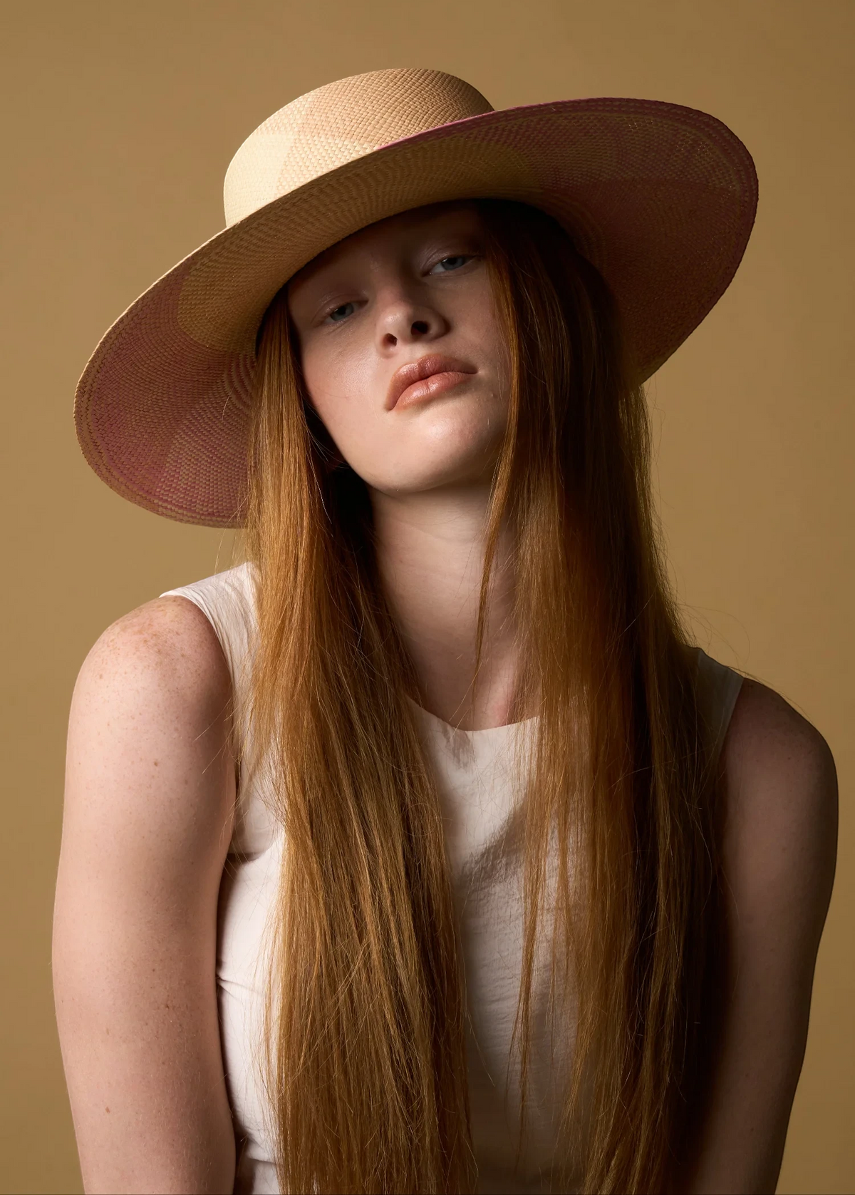 KABE SHOP INC Awisqa hat featuring a natural straw crown and wide pink brim worn by a model with long red hair