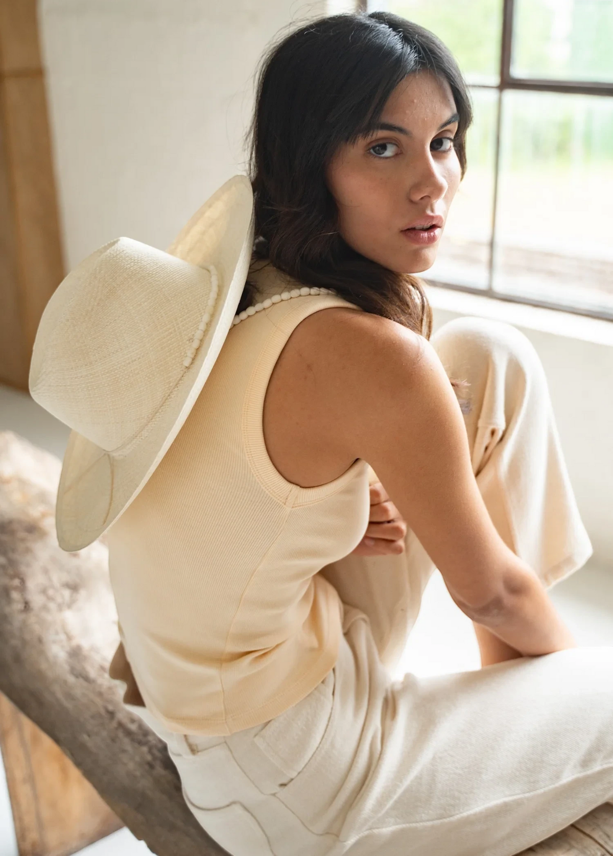 KABE SHOP INC Cajas wide brim straw hat worn by a woman in a cream tank top and trousers in a bright indoor setting