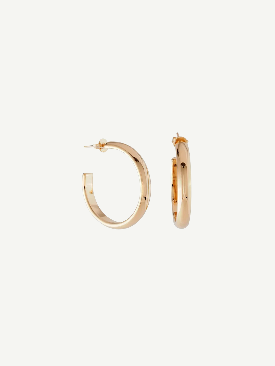 A pair of Irina Hoops 1.25″ featuring a shiny 14kt gold plate are displayed against a white background, with one earring shown front-facing and the other from the side to highlight their classic pierced back design.