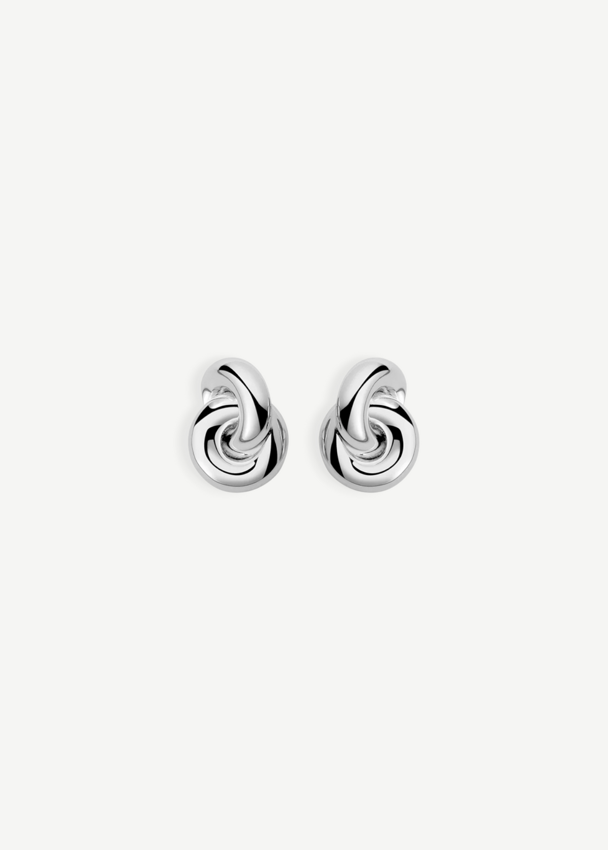 The Rhodium Amina Earrings are featured on a plain white background, showcasing an intricate interwoven knot design with a polished, shiny finish and a secure pierced back.