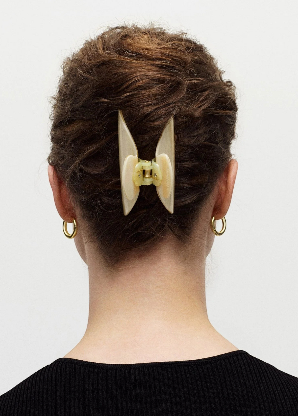 KABE SHOP INC Midi Heirloom hair claw in cream Italian acetate worn in a bun on a woman with gold hoop earrings