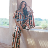 KABE SHOP INC Nera wide leg pants featuring a brown and white ikat print, worn by a woman in a sunny outdoor setting.