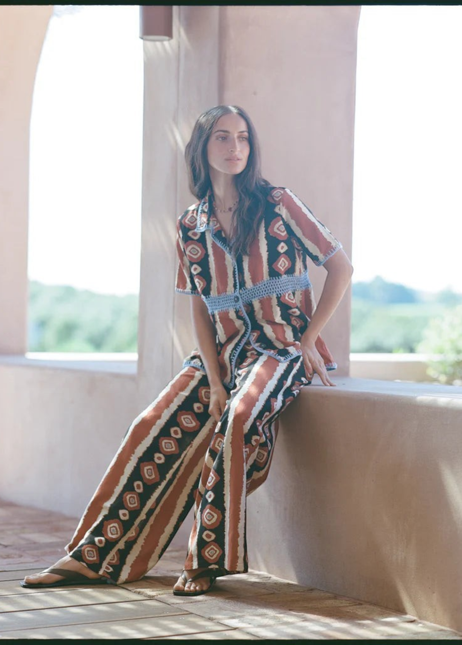 Model wearing KABE SHOP INC Nera wide leg pants with a tribal ikat print in rust, black, and white tones.