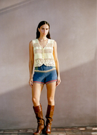 Model wearing a KABE SHOP INC Eva Vest, a cream-colored artisanal crochet button-down top with intricate detailing.
