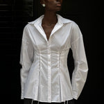 A person wears a white long-sleeve Laced Button Down featuring corset-style lace-up detailing at the waist to create a feminine silhouette.
