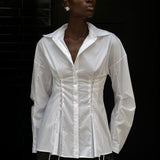 A person wears a white long-sleeve Laced Button Down featuring corset-style lace-up detailing at the waist to create a feminine silhouette.