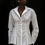 A person wears a white long-sleeve Laced Button Down featuring corset-style lace-up detailing at the waist to create a feminine silhouette.