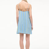 Back view of a person wearing a blue and green striped Laura Mini Dress with thin shoulder straps and flat sandals.