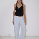 A person wears a black spaghetti strap camisole and light blue Deiji Studios Eyelet Pant, which are wide-leg pants with side eyelet detailing.