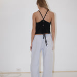 A person seen from behind wearing a black spaghetti-strap tank top with a tie back and light blue, straight-leg Eyelet Pant.