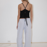 A person seen from behind wearing a black spaghetti-strap tank top with a tie back and light blue, straight-leg Eyelet Pant.