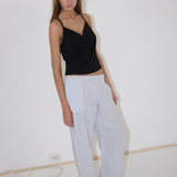 A person wearing a black camisole and white Eyelet Pant in a straight-leg silhouette, featuring loose-fitting fabric and a tied drawstring detail at the hip.
