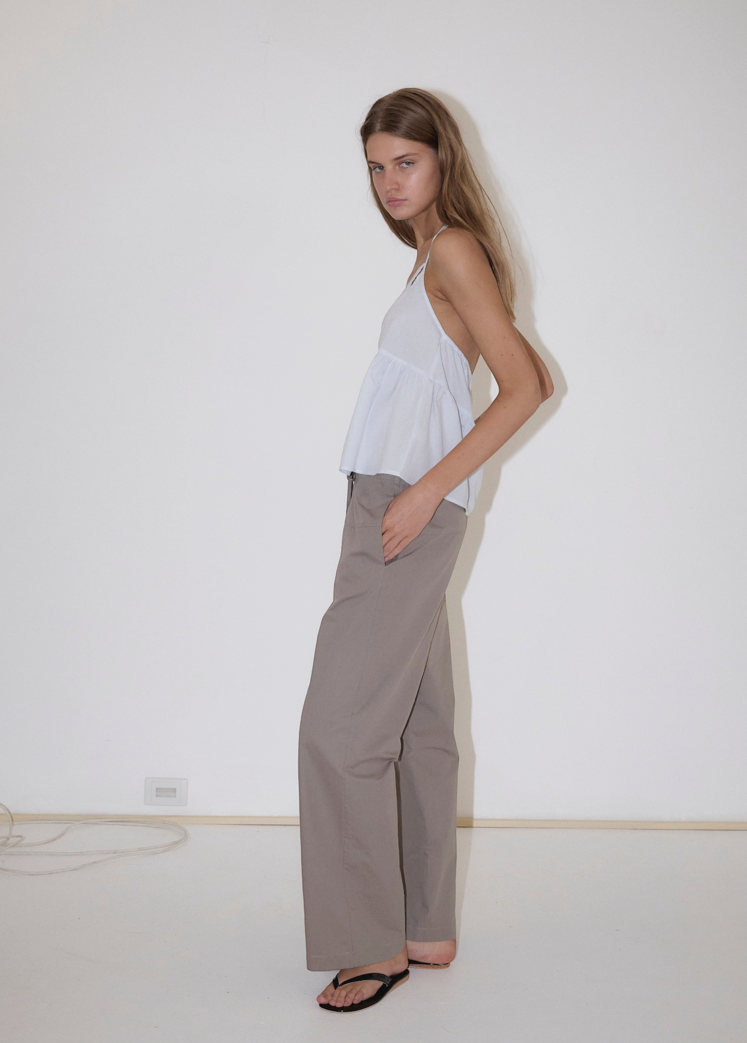 KABE SHOP INC Deiji Studios white keyhole halter top with thin straps worn by a model with grey trousers