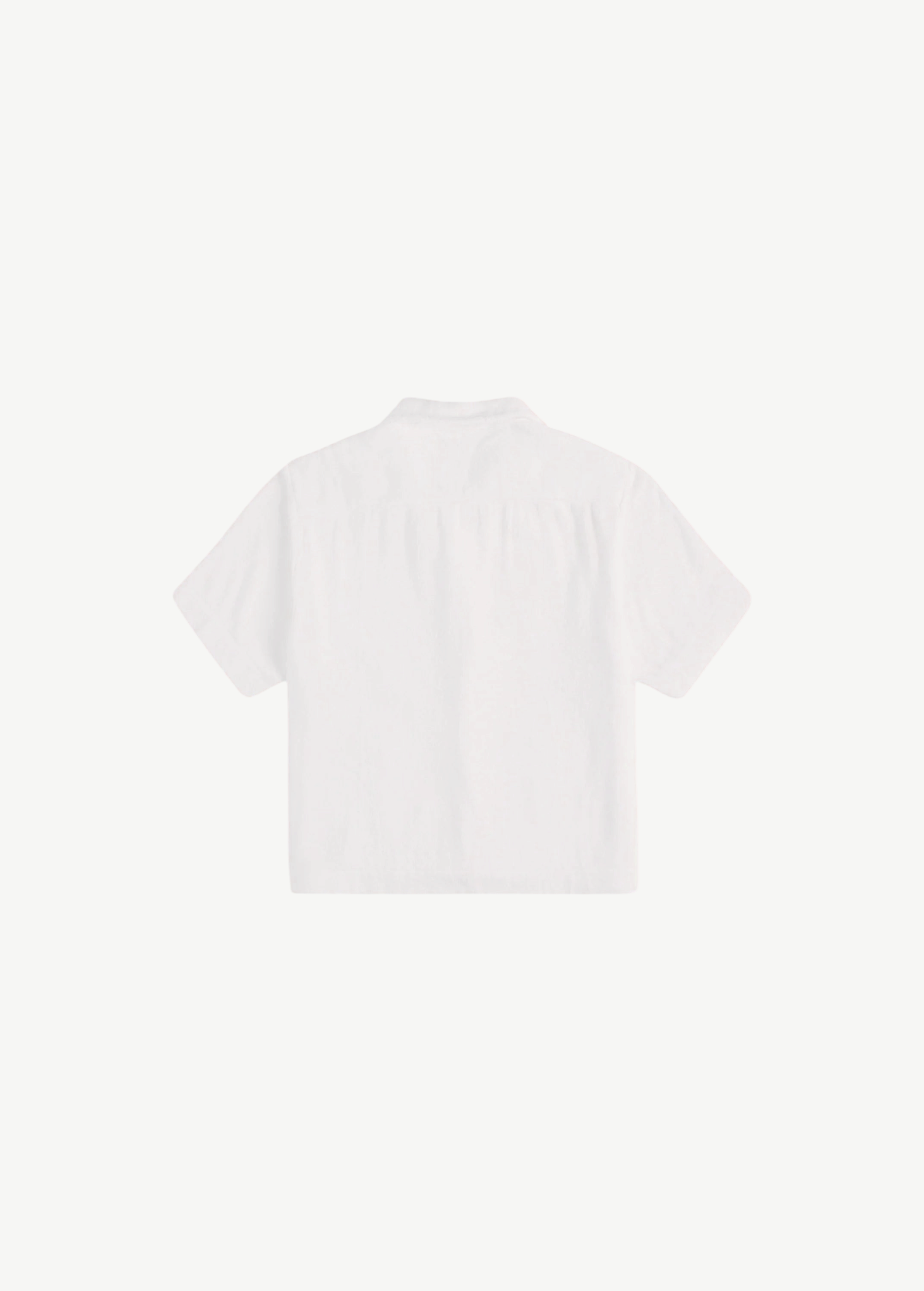 Back view of the white, short-sleeved Boxy Shirt Crochet in organic cotton, featuring a cropped, boxy fit and a crochet pocket.