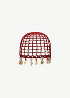 KABE SHOP INC Zahi Hat, a red crocheted skullcap featuring a grid pattern and dangling seashell and stone charms.