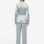 Back view of a person wearing a light blue crinkled Suki Shirt and matching trousers.