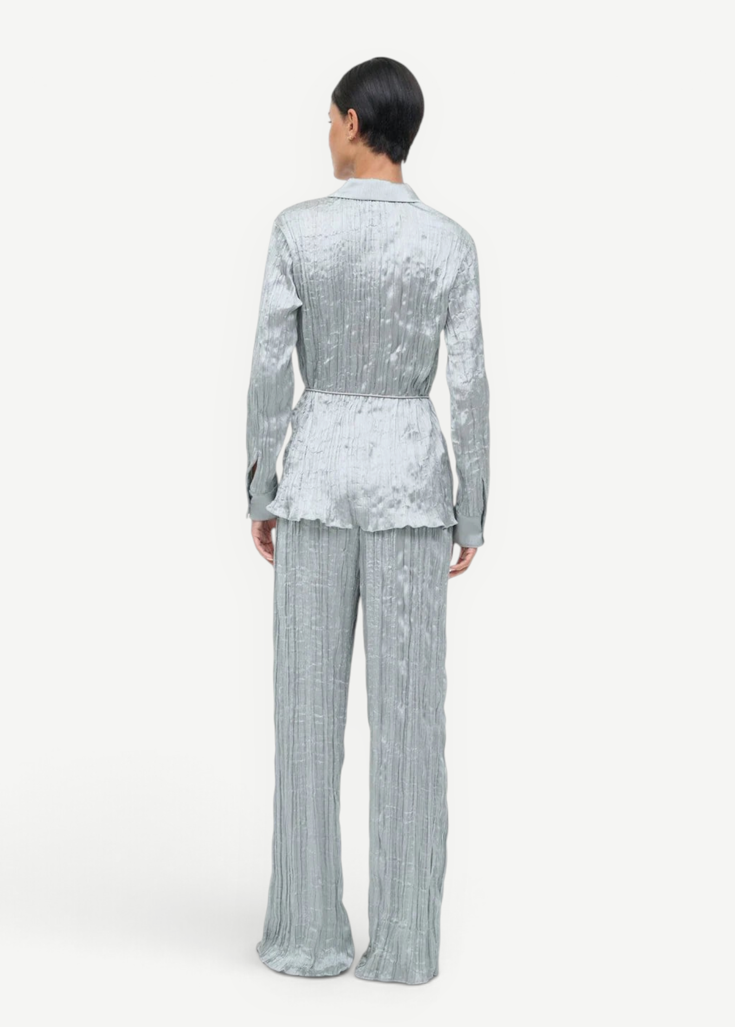 Back view of a person wearing a light blue crinkled Suki Shirt and matching trousers.