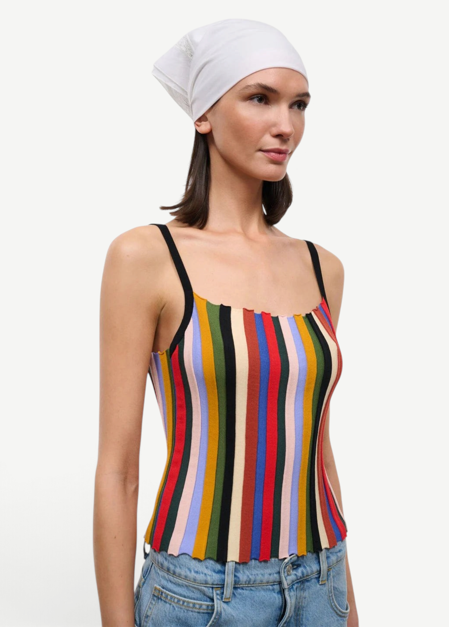 A person wearing a versatile Skye Tank with a square neckline, vertical multicolored stripes, and thin black straps, paired with a white headscarf and jeans.