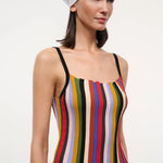 A person wearing a versatile Skye Tank with a square neckline, vertical multicolored stripes, and thin black straps, paired with a white headscarf and jeans.