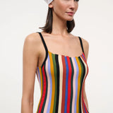 A person wearing a versatile Skye Tank with a square neckline, vertical multicolored stripes, and thin black straps, paired with a white headscarf and jeans.