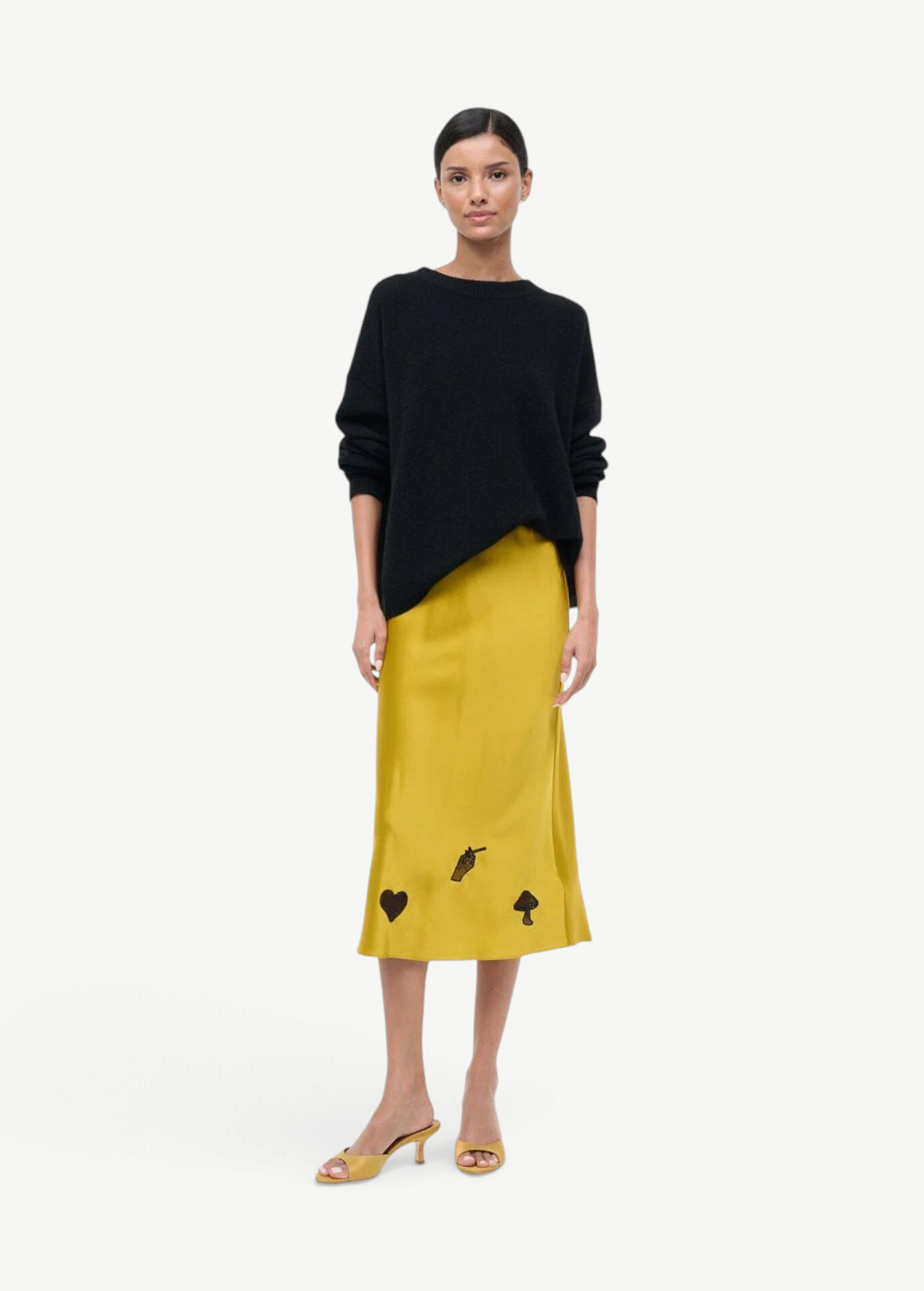 Model wearing KABE SHOP INC Brigitte mule heels in yellow with a black sweater and yellow midi skirt