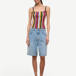 A person wears a multicolored, vertically striped Skye Tank, light-wash denim shorts, and brown platform flip-flops.