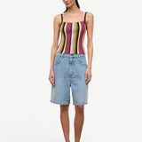 A person wears a multicolored, vertically striped Skye Tank, light-wash denim shorts, and brown platform flip-flops.