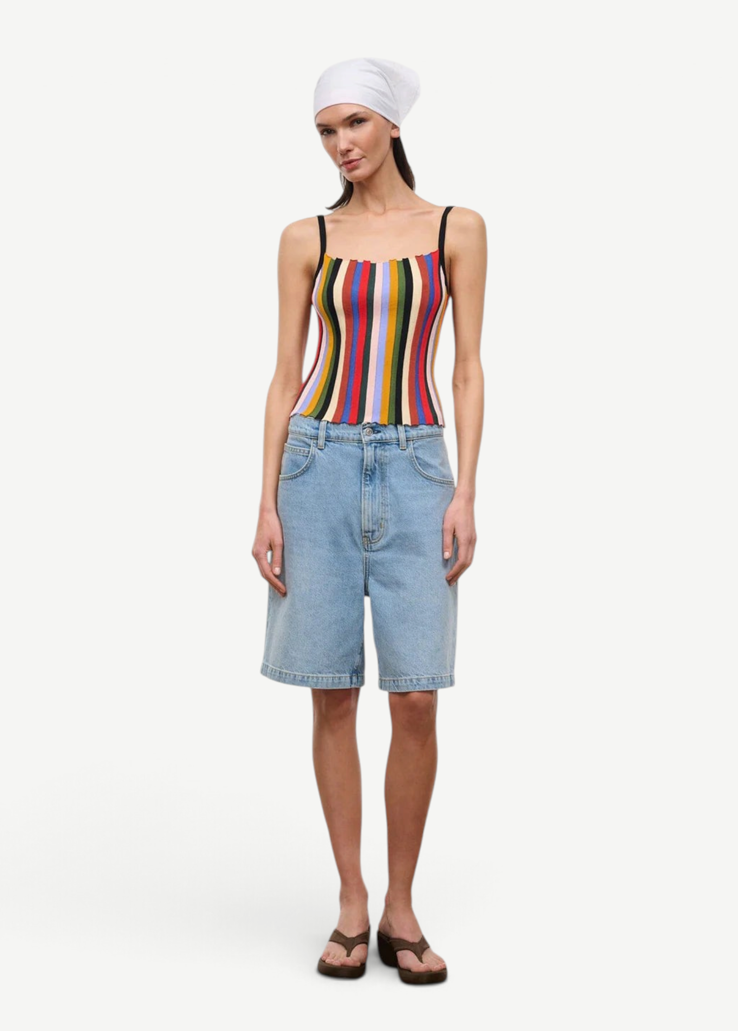 A person wears a multicolored, vertically striped Skye Tank, light-wash denim shorts, and brown platform flip-flops.