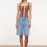 A person wears a multicolored, vertically striped Skye Tank, light-wash denim shorts, and brown platform flip-flops.