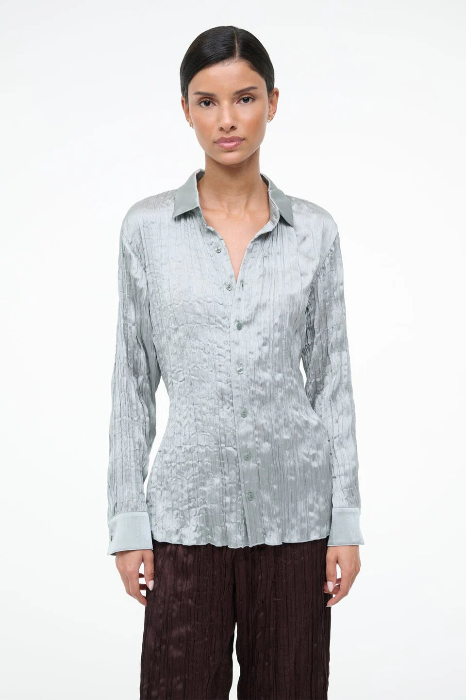 A model wearing the Suki Shirt, a light sage, long-sleeved button-down with a crinkled texture that serves as a versatile wardrobe essential.
