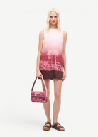 KABE SHOP INC Tommy beaded shoulder bag with pink California palm tree print held by a model in a matching dress
