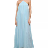 A floor-length, light blue Dasha Dress with a pleated halter-neck design, styled with silver strappy sandals for a minimalist summer look.
