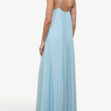 A person wearing a light blue, floor-length Dasha Dress with a minimalist design and spaghetti straps.
