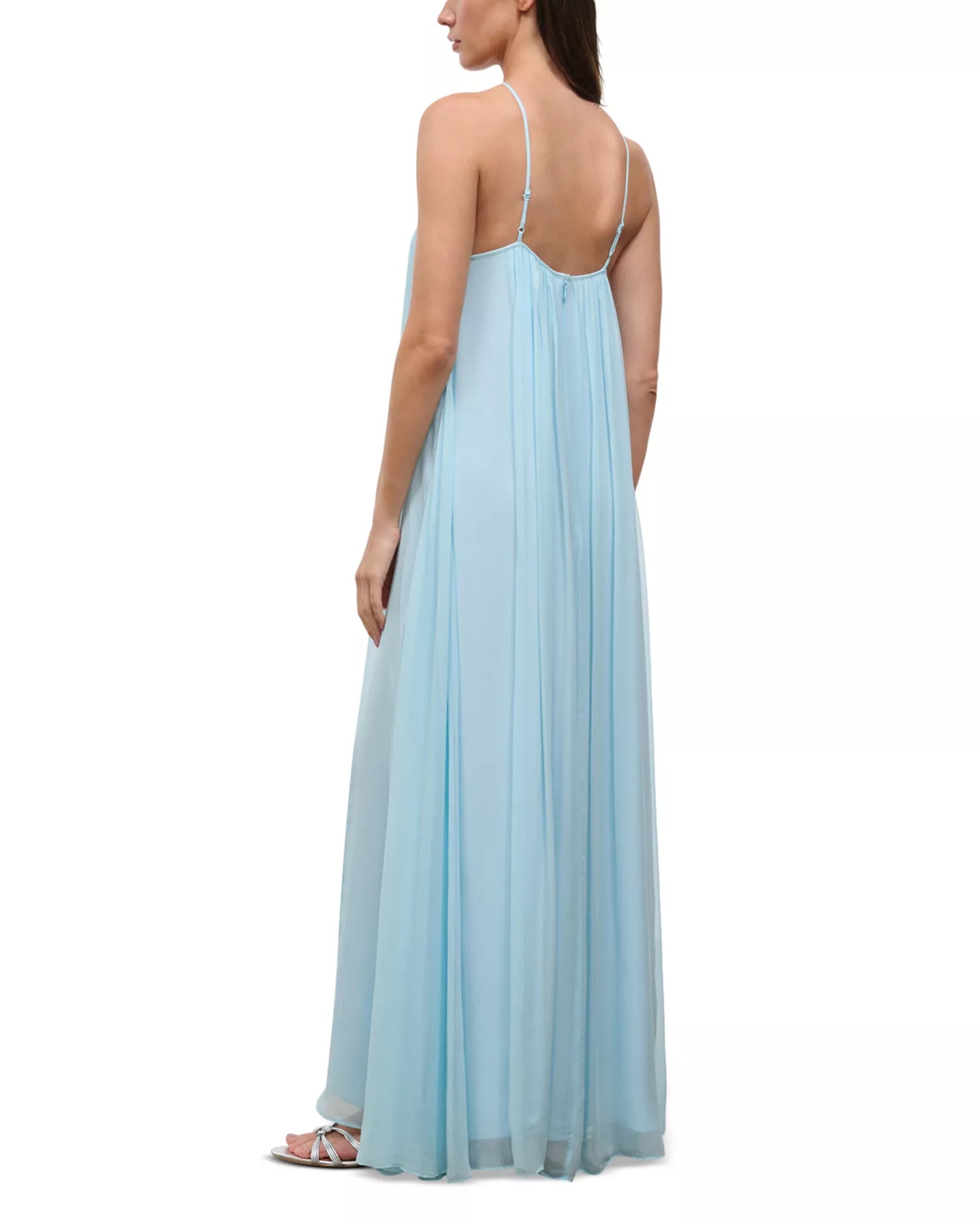 A person wearing a light blue, floor-length Dasha Dress with a minimalist design and spaghetti straps.