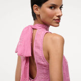A person wears the pink Mini Albee Dress, an elegant mini dress featuring a sophisticated silhouette with a high neck, open back, and beaded floral embroidery.
