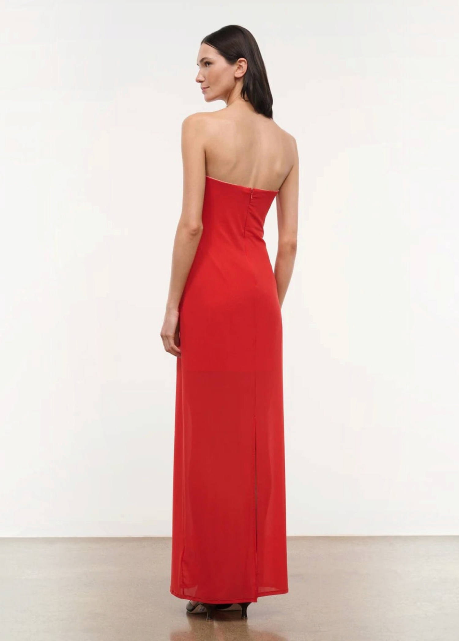 A person viewed from behind wearing the floor-length red Liliana Dress, a strapless gown perfect for special occasions.