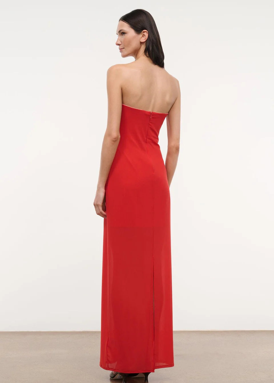 A person viewed from behind wearing the floor-length red Liliana Dress, a strapless gown perfect for special occasions.