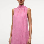 The Mini Albee Dress is a sleeveless, high-neck mini dress in pink featuring textured floral embroidery and an attached side scarf for a sophisticated silhouette.